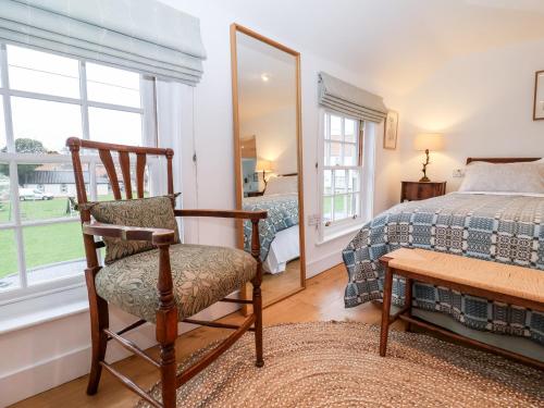 a bedroom with a chair and a bed and a mirror at Beta Cottage in Southwold