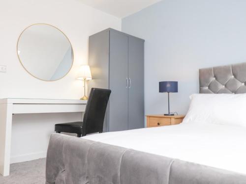 a bedroom with a bed and a desk and a mirror at Blue Bay Villa in Holyhead