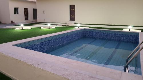 ein großer Pool mit Lichtern in einem Gebäude in der Unterkunft شالية المزرعة 