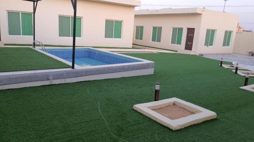 einen großen Garten mit Pool und grünem Gras in der Unterkunft شالية المزرعة 