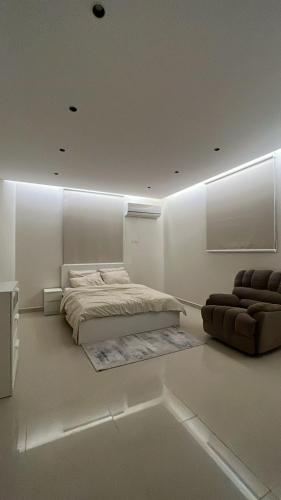 a white bedroom with a bed and a couch at شقة بغرفة نوم وصالة in Unayzah