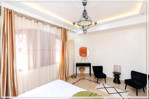 um quarto com uma cama, 2 cadeiras e uma janela em Fabuleuse Villa Marrakchi em Marrakech
