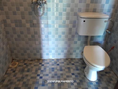 een badkamer met een toilet en blauwe tegels bij Pelican Resort Beach in Kalangala