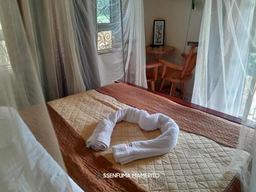 Kalangala的住宿－Pelican Resort Beach，一条像心形的毛巾,坐在床上
