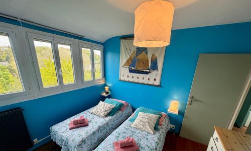 ein Schlafzimmer mit 2 Betten und einer blauen Wand in der Unterkunft Le Repos des Rias, maison au cœur de la ville in Quimperlé
