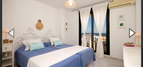 a bedroom with a blue and white bed and a window at Las Casas de Mar Atlanterra in Zahara de los Atunes
