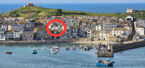 a group of boats in the water near a town at AMAZING LOCATION - "SMUGGLERS HIDE" & "SMUGGLERS CABIN" - a 2 BEDROOM FISHERMANS COTTAGE with HARBOUR VIEW and also a private entrance 1 BED STUDIO - 10 Metres To Sea Front - BOOK BOTH for ENTIRE 3 BEDROOM COTTAGE - 2023 GLOBAL REFURBISHMENT AWARD WINNER in St Ives