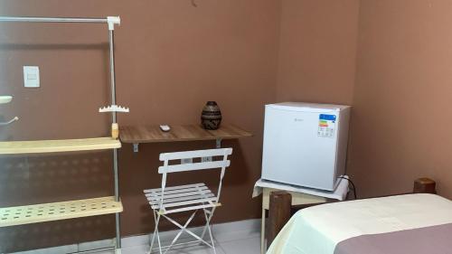 a kitchen with a refrigerator and a table and a chair at Pousada e Restaurante Mar dos Sonhos in Paripueira