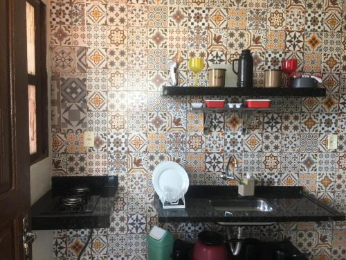 a kitchen with a sink and a tile wall at Recanto do Hibisco in Prado