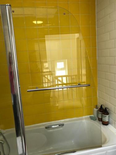 a yellow tiled bathroom with a tub with a glass door at Spacious 3 bed townhouse in Dublin 12 in Dublin