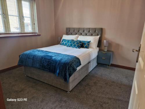 a bedroom with a large bed with a blue blanket at LanEnd House in Whiston