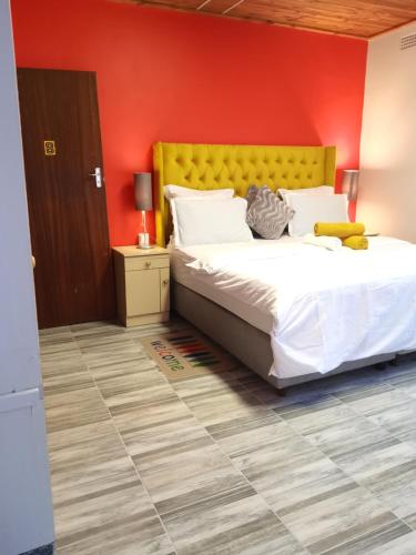 1 dormitorio con cama y pared roja en Neo & Ruks Bellville Guesthouse, en Ciudad del Cabo