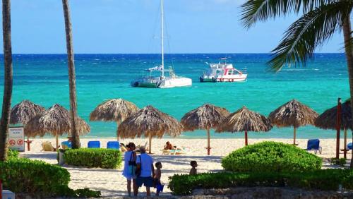 grupa ludzi na plaży z łodziami w wodzie w obiekcie SOL CARIBE SUITES - PLAYA LOS CORALES - beach club, wifi, swimming pool w Punta Cana