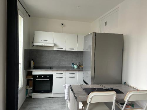- une cuisine avec des placards blancs, une table et un réfrigérateur dans l'établissement Studio très lumineux et équipée en pleine avenue !, au Kremlin-Bicêtre