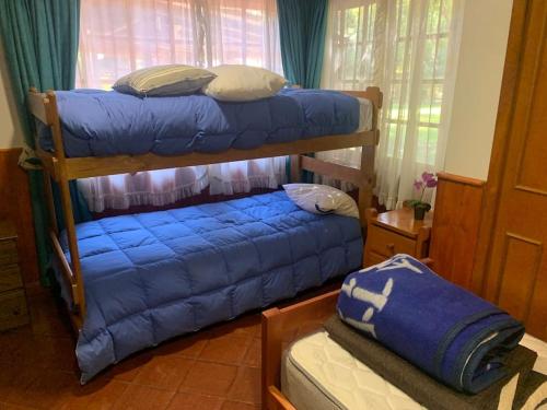 a bedroom with two bunk beds with blue sheets at EL REFUGIO DE NAELA in Coltauco