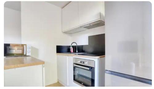 une cuisine avec des armoires blanches et un four à plaques de cuisson dans l'établissement Comme Chez Vous Appartement 2 Chambres, à Nanterre