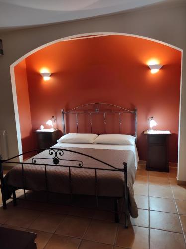 a bedroom with a large bed with an orange wall at Le Residenze di Niso in Syracuse