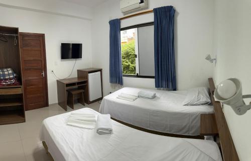 a hotel room with two beds and a window at Hotel 15 de Julho in Foz do Iguaçu
