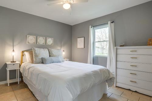 a bedroom with a white bed with a dresser and a window at Benton Harbor Home with Fire Pit - 2 Mi to Beach! in Benton Harbor