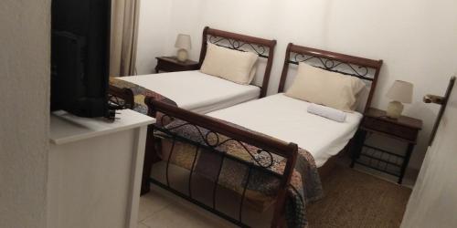 two twin beds in a room with a television at Villa Victoria in Gradac