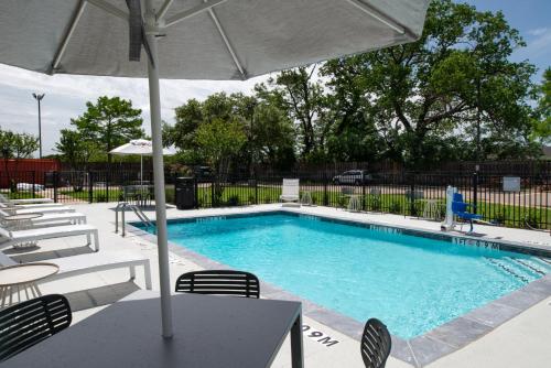 a swimming pool with chairs and an umbrella at Spark By Hilton Dallas Medical District Love Field in Dallas