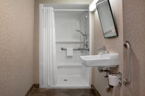 a bathroom with a white shower and a sink at Ramada Plaza by Wyndham Calgary Downtown in Calgary