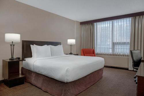 a hotel room with a large bed and a red chair at Ramada Plaza by Wyndham Calgary Downtown in Calgary