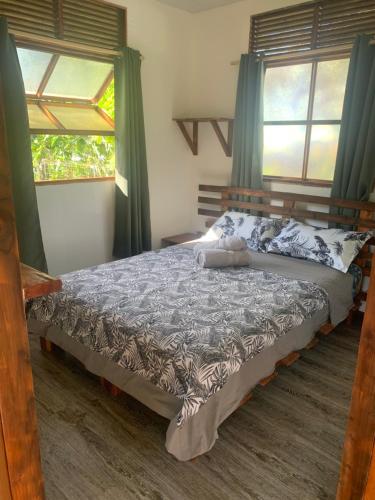 a bed in a bedroom with two windows at Fare lei , bungalow en toute simplicité in Uturoa