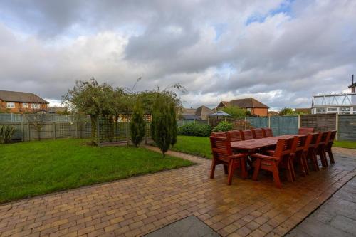 a wooden table and chairs on a brick patio at Supreme Class Properties in Eastchurch
