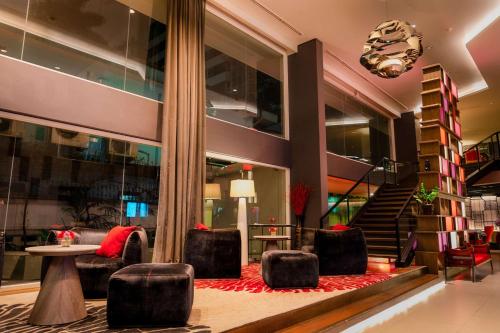 a lobby with chairs and a table and stairs at Park Plaza Bangkok Soi 18 in Bangkok