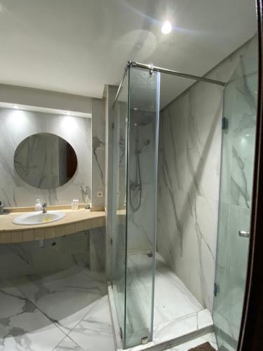 a bathroom with a glass shower and a sink at cozy apprtr in Agadir