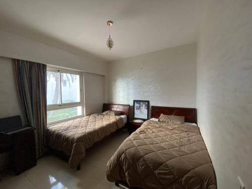 - une chambre avec 2 lits et une fenêtre dans l'établissement cozy apprtr, à Agadir