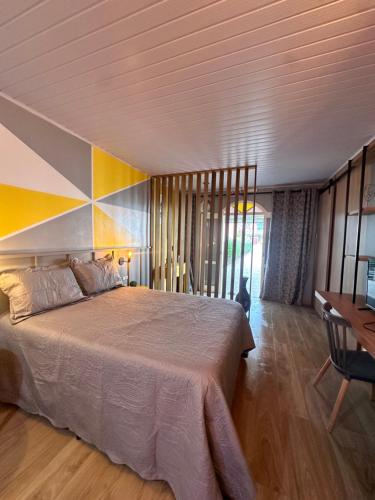 a bedroom with a large bed and a desk at La vita hospedaria (quarto amarelo) in Nova Veneza