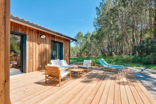 a wooden deck with chairs and a table at Peaceful house on the edge of a forest in Sanguinet