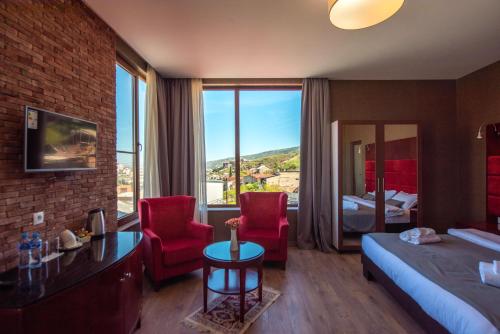 pokój hotelowy z łóżkiem i 2 czerwonymi krzesłami w obiekcie Kraveli Hotel w mieście Tbilisi City