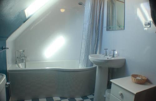 y baño con lavamanos, bañera y lavamanos. en Comfortable detached 4 bedroomed holiday home en Balivanich