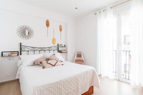 ネルハにあるApartamento Serendipia Nerjaの白いベッドルーム(白いシーツと鏡付きのベッド付)