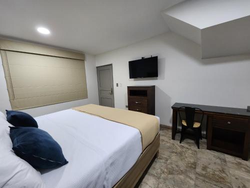 a bedroom with a bed and a desk and a television at Hotel Roque in Torreón