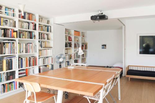 une salle à manger avec une table et des étagères dans l'établissement Spacious cocoon with a terrace view on the canal, à Paris