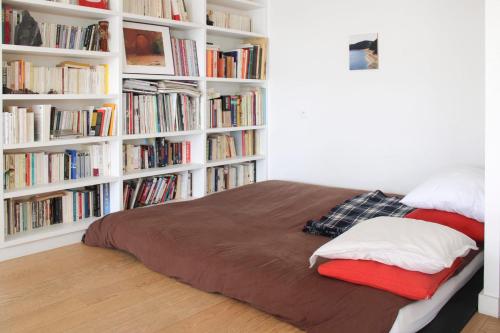 une chambre avec un lit avec des étagères remplies de livres dans l'établissement Spacious cocoon with a terrace view on the canal, à Paris