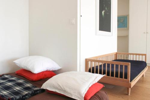 - un lit avec 2 oreillers et un lit bébé dans l'établissement Spacious cocoon with a terrace view on the canal, à Paris