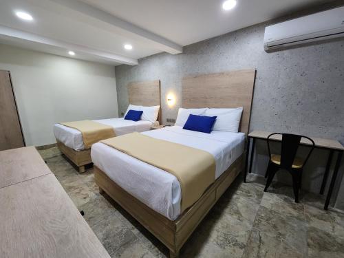 um quarto de hotel com duas camas e uma mesa em Hotel Roque em Torreón