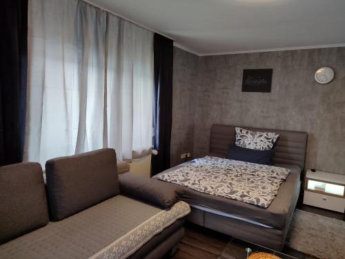 a small bedroom with a bed and a couch at Ferienwohnung Rhein-Main II in Flörsheim