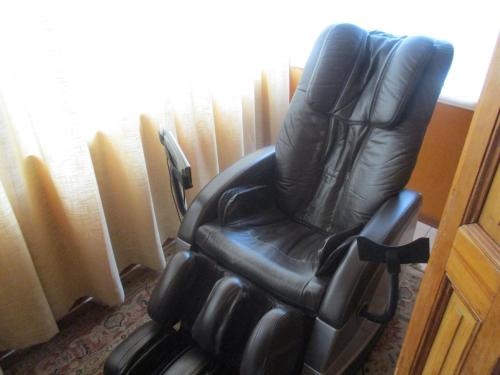 a black leather chair sitting next to a window at Hotel Boutique Las Azucenas in Constitución