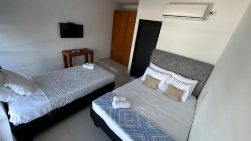 a hotel room with two beds and a television at Rio-ApartaHotel-Lagos in Leticia