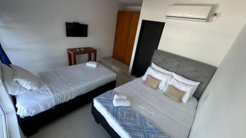 a hotel room with two beds and a television at Rio-ApartaHotel-Lagos in Leticia