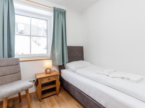 a bedroom with a bed and a chair and a window at Lärchenhof Top 203 in Mauterndorf
