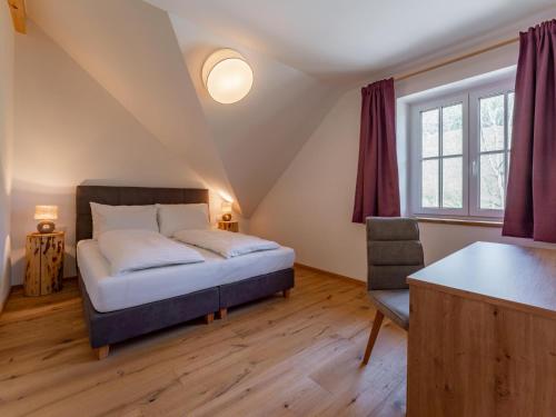 a bedroom with a bed and a chair in a attic at Lärchenhof Top 303 in Mauterndorf