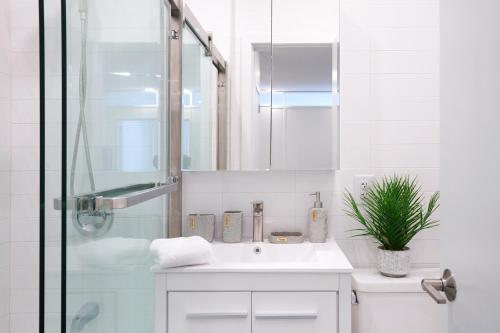 uma casa de banho branca com um lavatório e um chuveiro em 444-2C Newly renovated 1BR in Hell's Kitchen em Nova York
