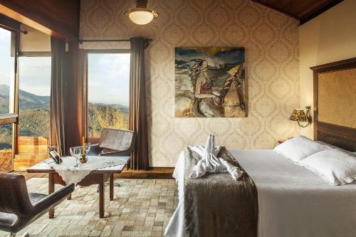 a bedroom with a bed and a table and a window at Canto dos Prazeres Lavras Novas in Lavras Novas